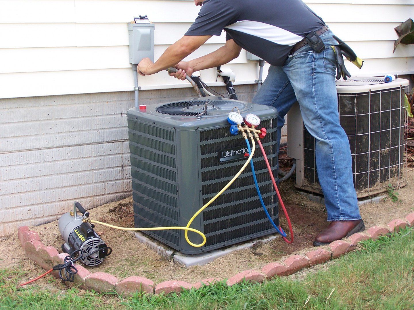 HVAC technician checking refrigerant pressure on an outdoor condenser