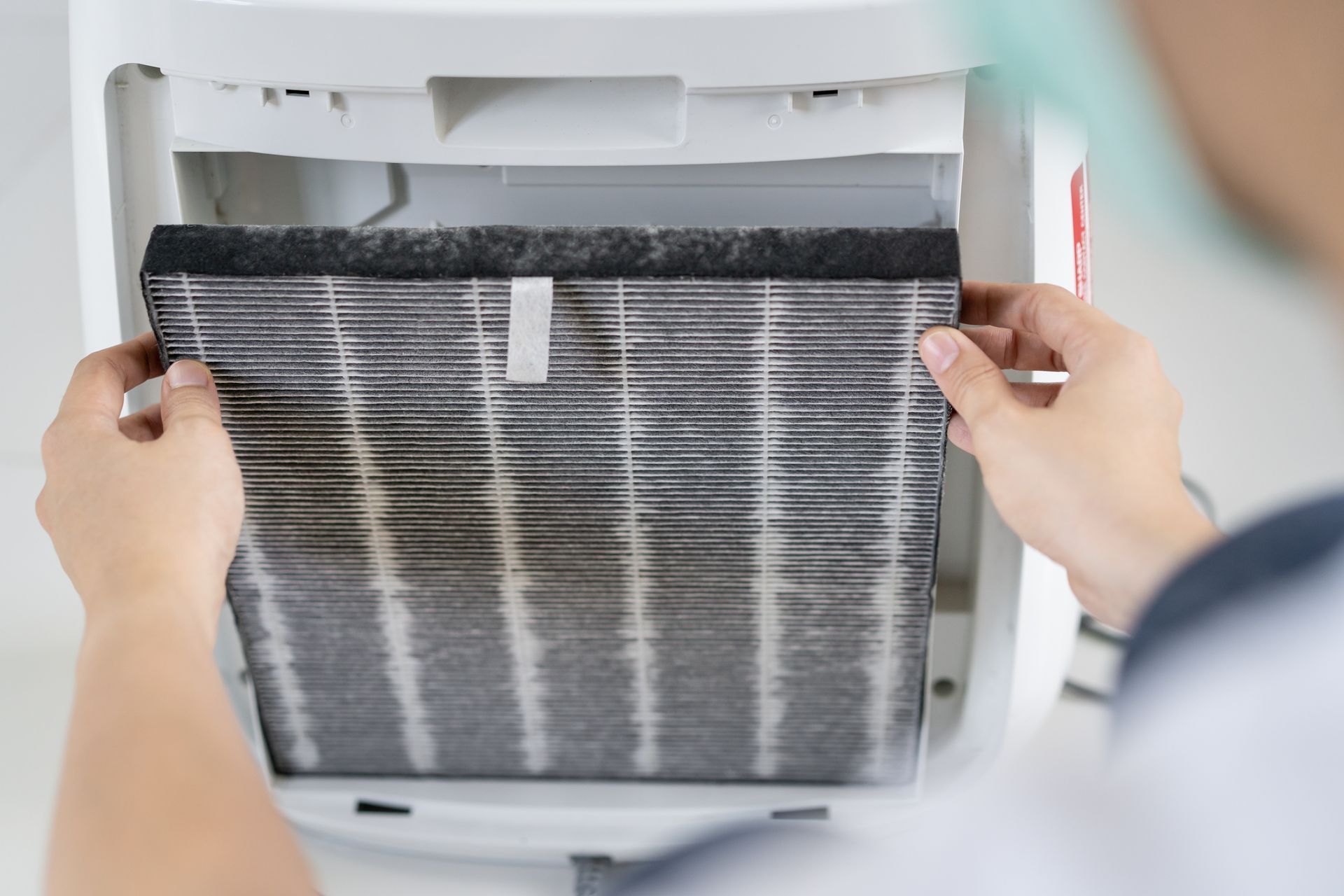 Technician pulling a clogged, dust-caked filter out of an air conditioner