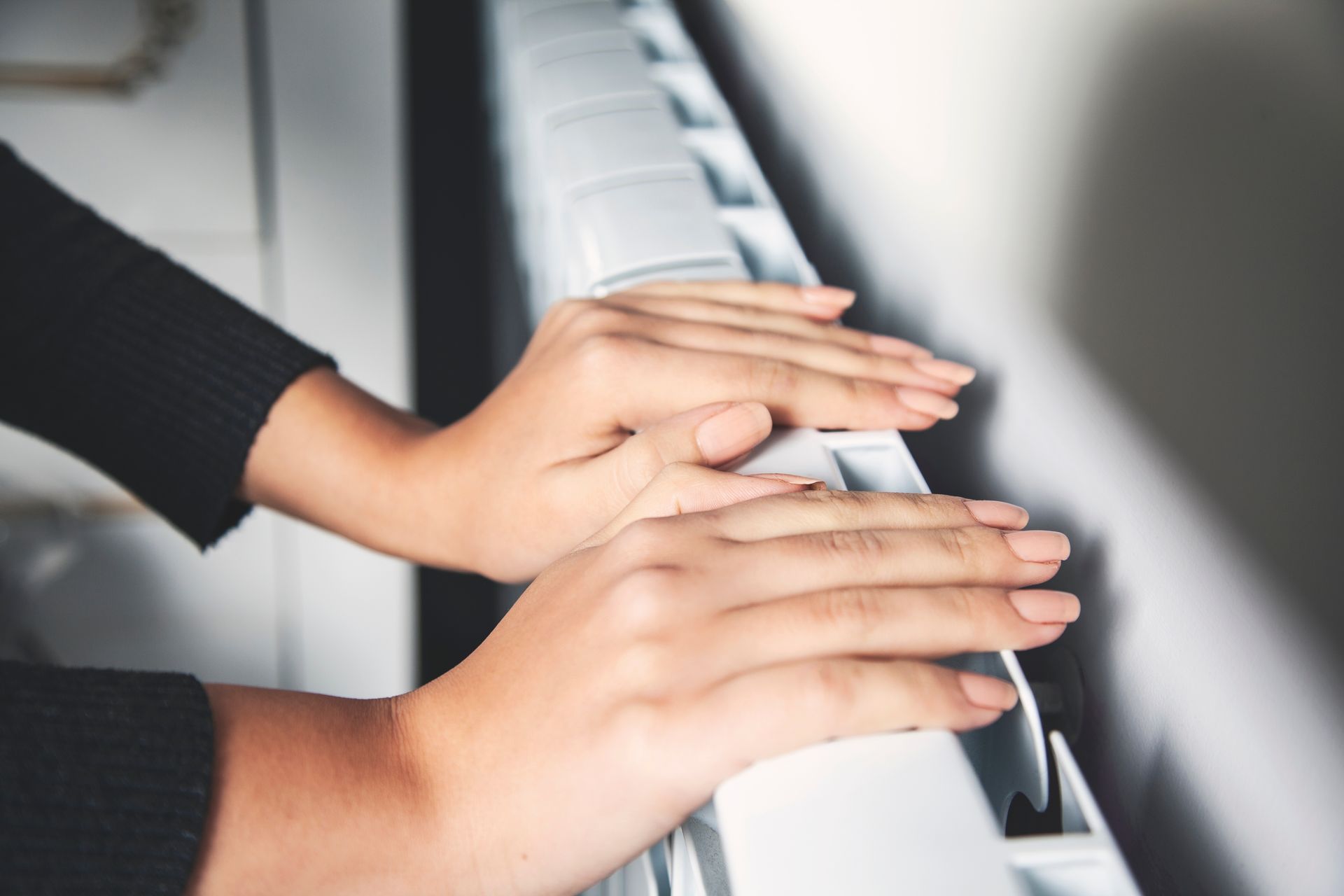 Hands warming over a home radiator during winter