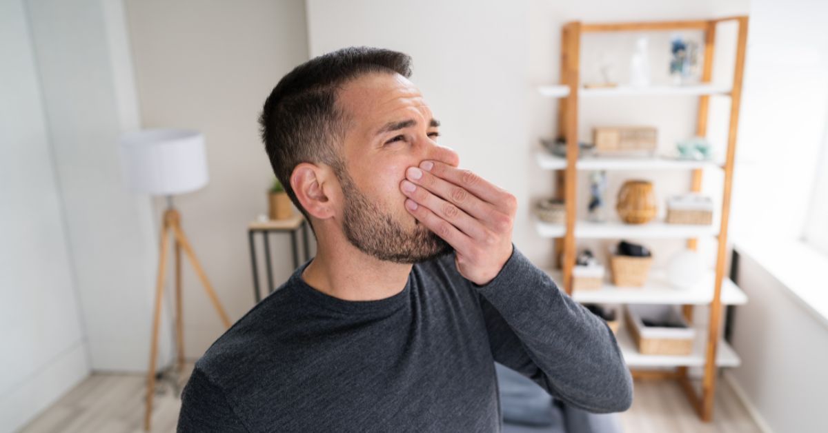 Man covering his nose at a burning smell from his heating system
